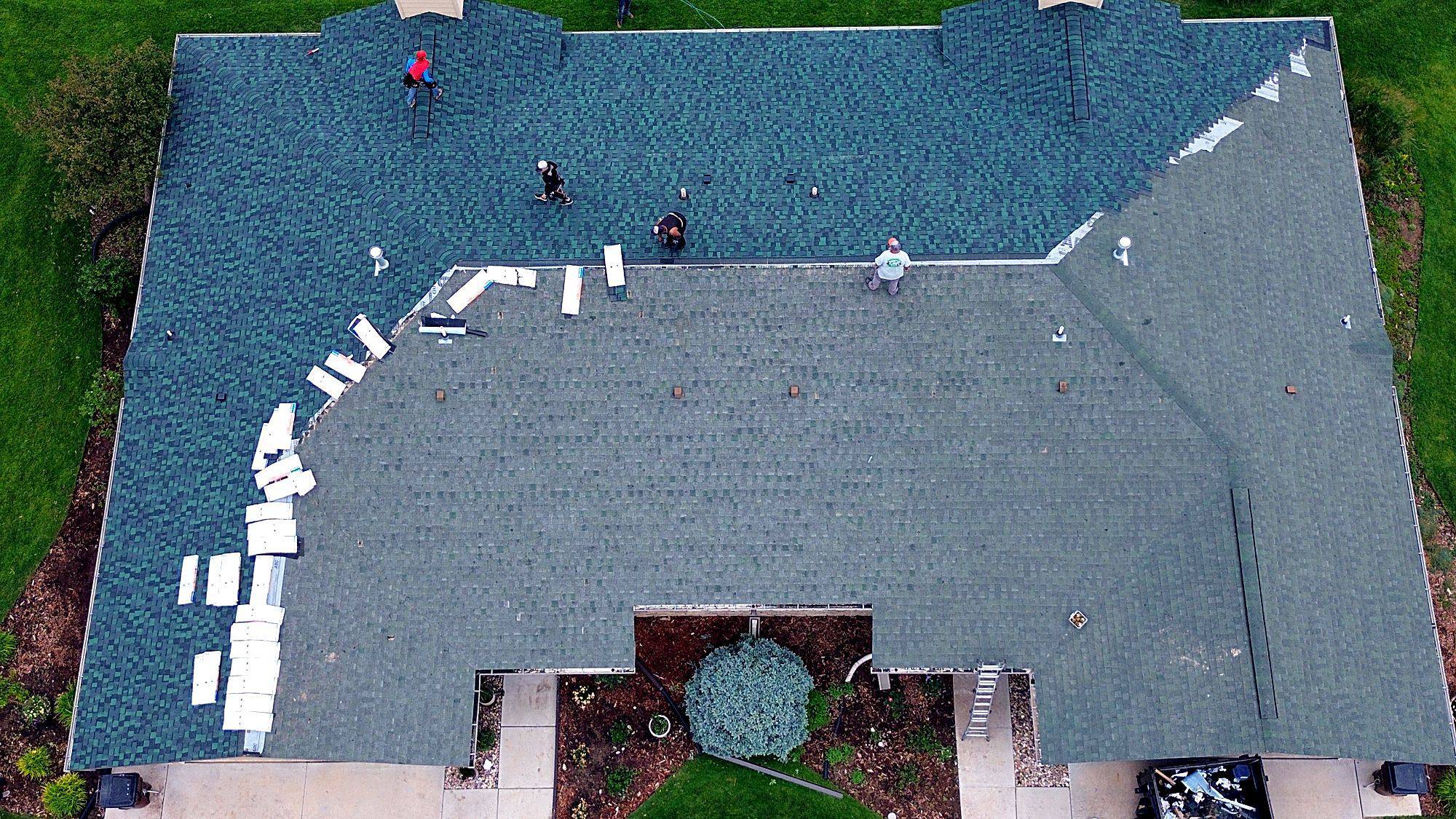 Direct overhead aerial of a residential roof mid-replacement, new shingle meeting old