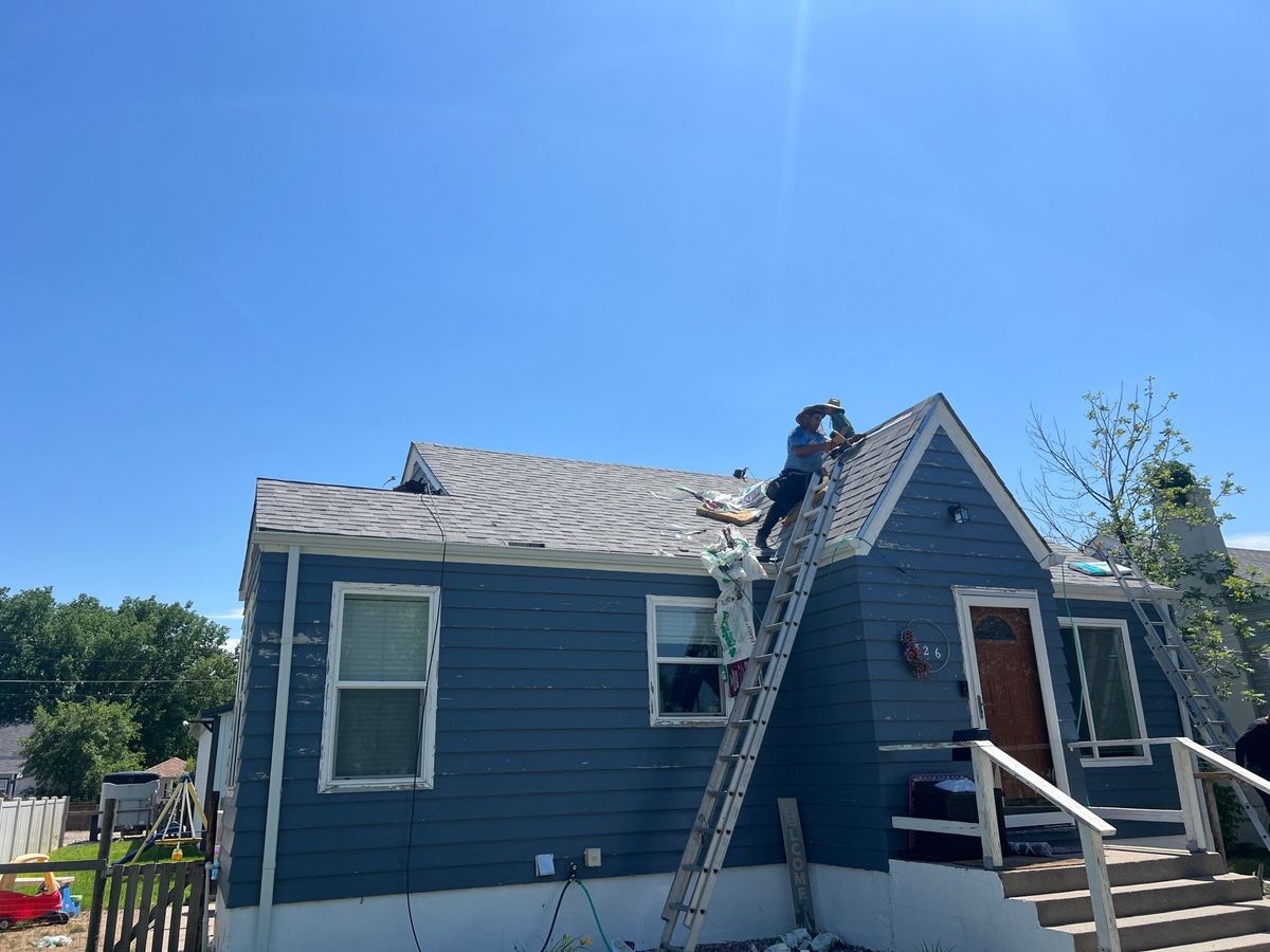 Schank Roofing crew member on a ladder at the roof edge during an inspection